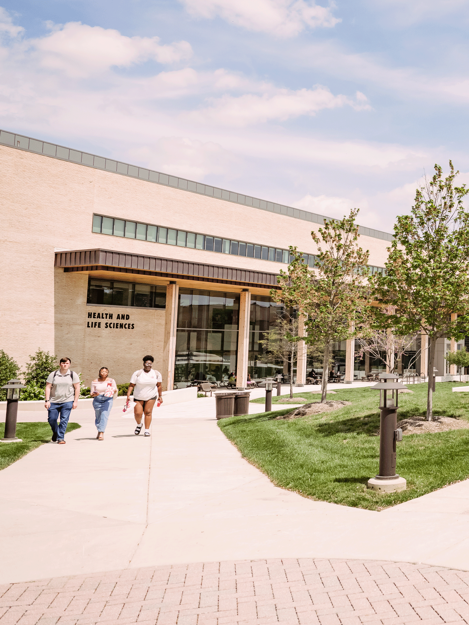 Three students walking in front of the Health and Life Sciences Building