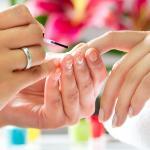 A nail tech applies polish to a clients nails.